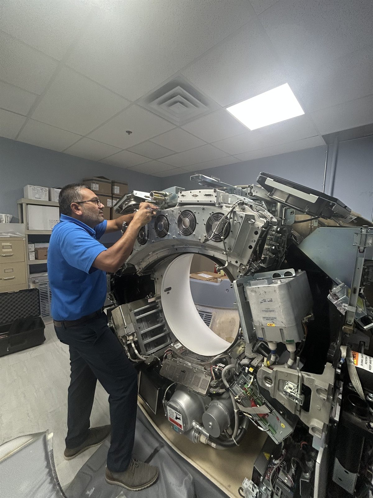 ClearMed co-founder Ankur Patel servicing a GE CT scanner with the gantry covers removed